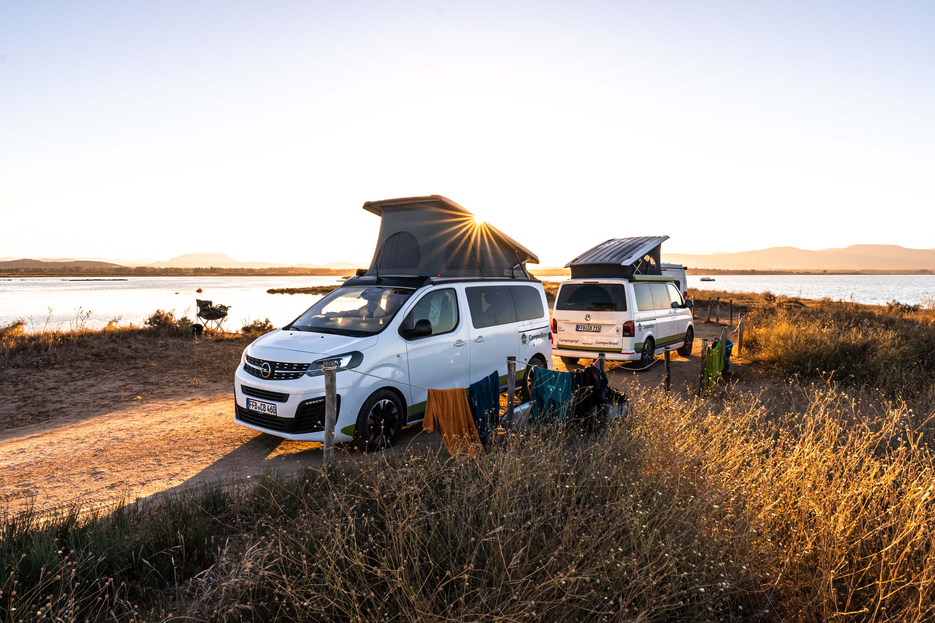 Opel Crosscamp and VW California stand in front of a sunset