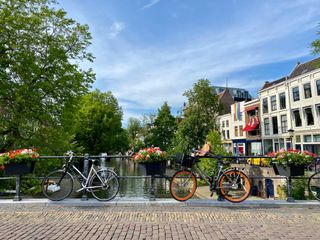 Zwei Fahrräder gelehnt an eine Brücke über der Gracht mit Bäumen und Häusern im Hintergrund: Utrecht ist ein Must-see auf einer Reise durch Holland mit dem Camper