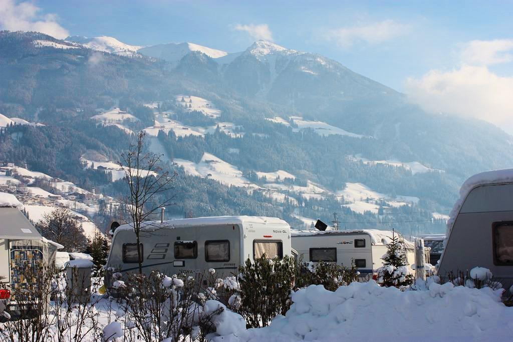 Der Campingplatz Natürlich Hell im Winter. Man sieht die Berge im Hintergrund und einige Wohnmobile auf dem Platz.