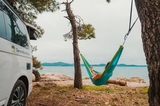 Person in der Hängematte neben einem Camper im Kroatien Urlaub
