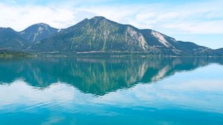 Blick vom Wasser aus auf den türkisblauen Walchensee in Oberbayern und die Berge
