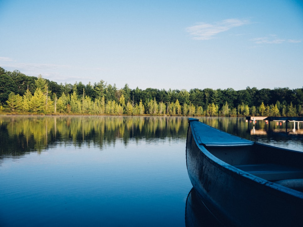 Naturnahes Camping am Steinbachsee: Spiegelglattes Wasser, ein Ruderboot vor bewaldetem Ufer