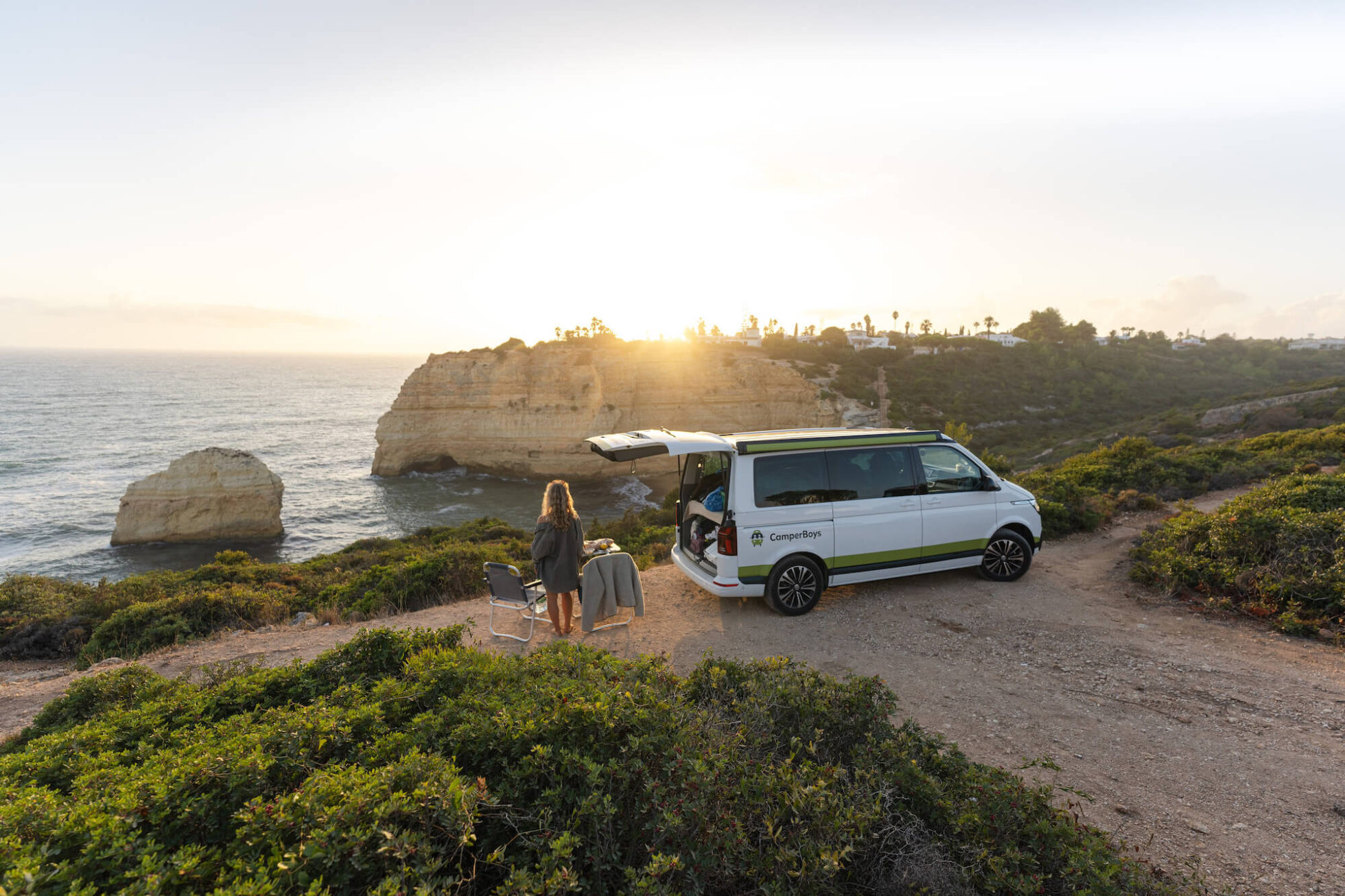 VW T6.1 California Beach Ocean steht vor Klippen zum Sonnenuntergang