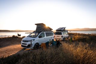 Camping Nebensaison: zwei Camper an einem Stellplatz an der Küste beim Sonnenuntergang
