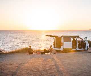Camper an der Küste von Sardinien: Paar macht Yoga am Strand