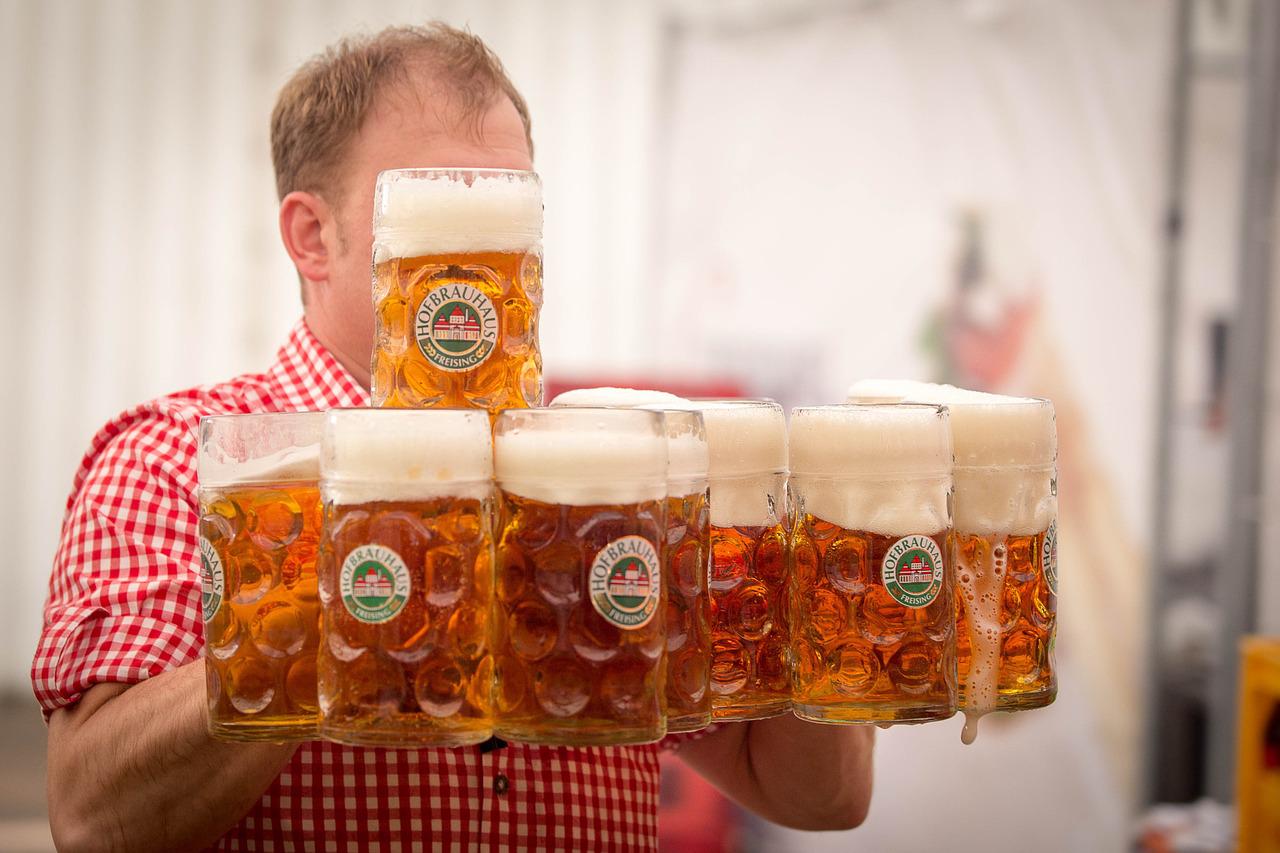 Kellner auf Oktoberfest trägt 10 Maß Hofbräuhaus Maßkrüge voller Bier 
