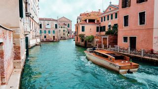 Kleines Boot fährt durch einen Kanal in Italien.