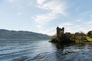 Der Loch Ness mit der Ruine von Schloss Urquhart an seinem Ufer.