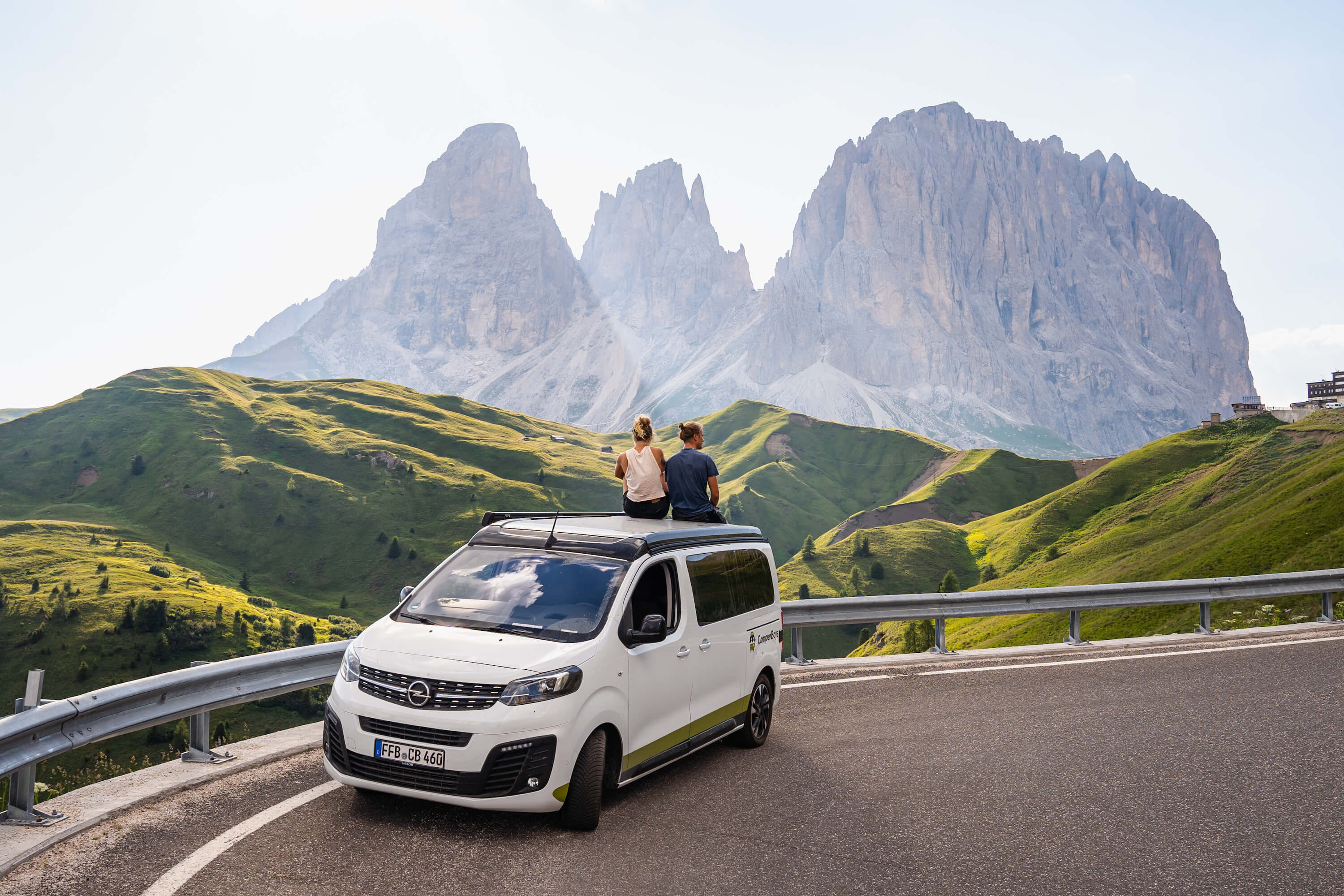 Couple sits on Opel Crosscamp in the mountains